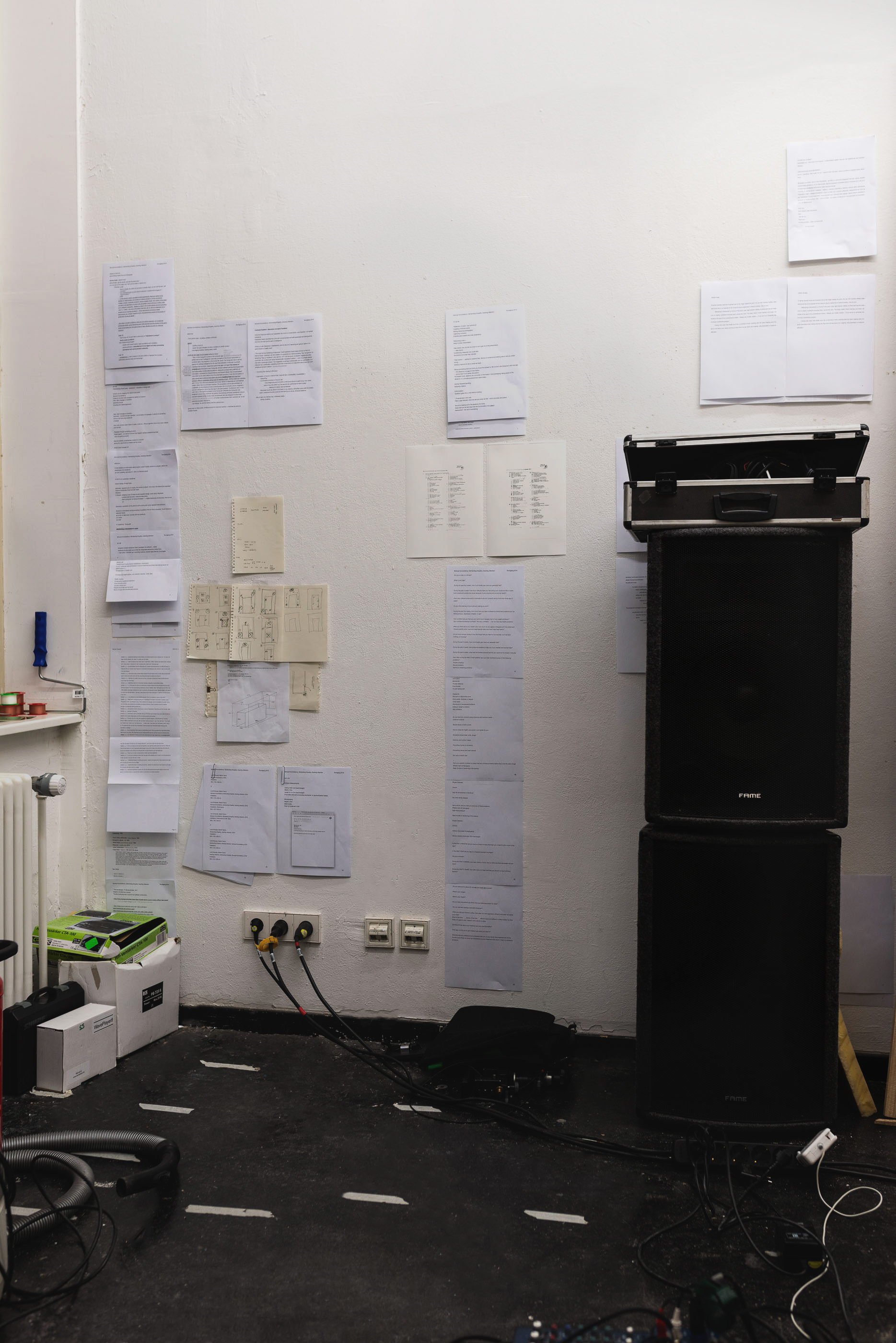 Wall of the outer room covered in documents, writings, drawings along with two stacked speakers. This view is inaccessible from the inside of the built in box.